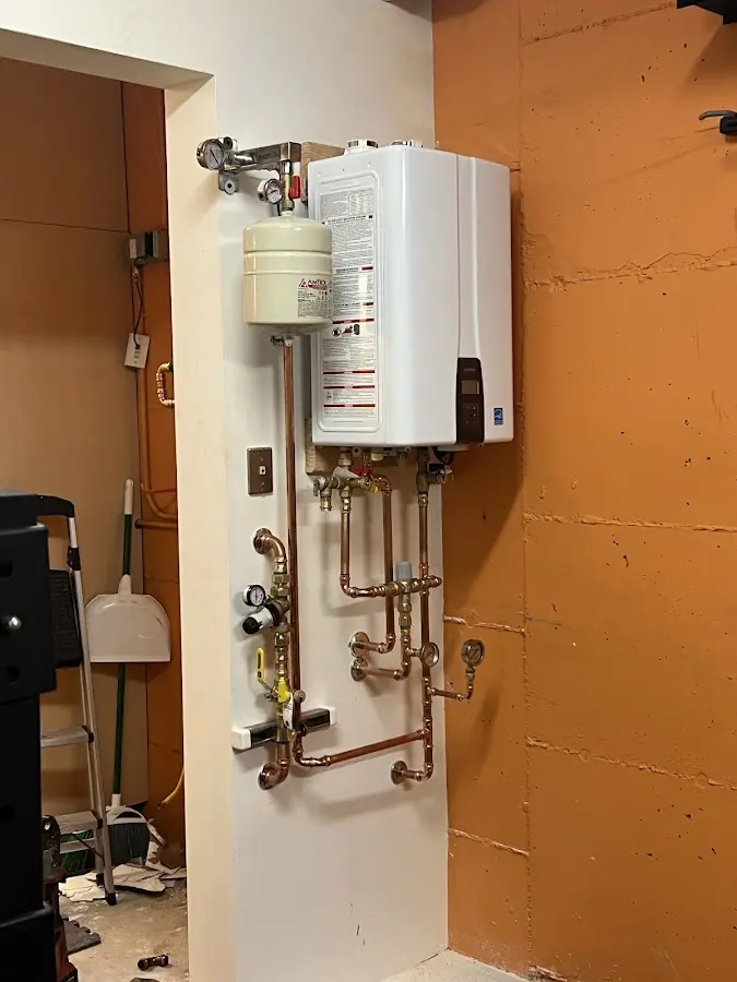 Plumbing technician inspecting water heater connections in East Greenwich